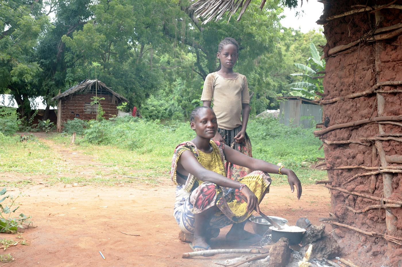 A Kenyan mother with her children outside their home